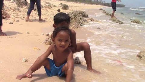 SULANGAN, PHILIPPINES - CIRCA MARCH 2017:  Filipino kids play on a beach on the ocean near the village of Sulangan, Eastern Samar, Philippines.