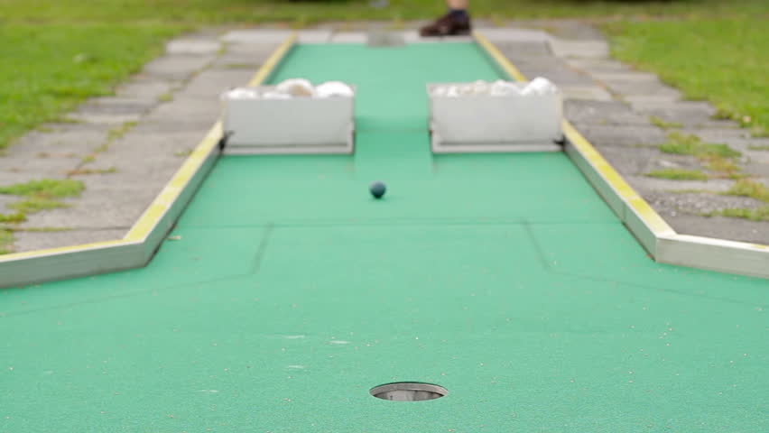 Young woman playing mini-golf during cloudy day, selective focus, successful