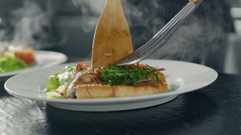 Close-up Serving Fish on a Plate Decorated with Vegetables and Salat..  Shot on RED EPIC-W 8K Helium Cinema Camera.