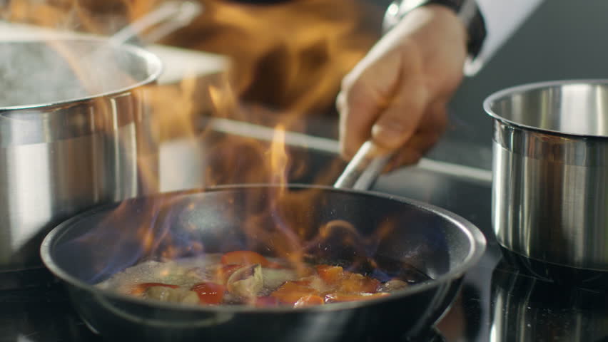 Close-up of a Chef Preparing Flambe Style Dish on a Pan. Oil and Alcohol Ignite with Open Flames. Shot on RED EPIC-W 8K Helium Cinema Camera. Royalty-Free Stock Footage #28204189