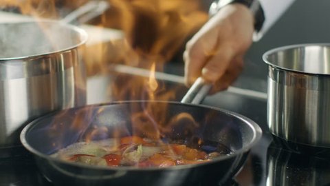 Close-up of a Chef Preparing Flambe Style Dish on a Pan. Oil and Alcohol Ignite with Open Flames. Shot on RED EPIC-W 8K Helium Cinema Camera.