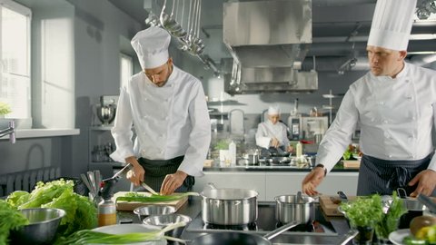 Two Famous Chefs Work as a Team in a Big Restaurant Kitchen. Vegetables and Ingredients are Everywhrere, Kitchen Looks Modern with Lots of Stainless Steel.   Shot on RED EPIC-W 8K Helium Cinema Camera