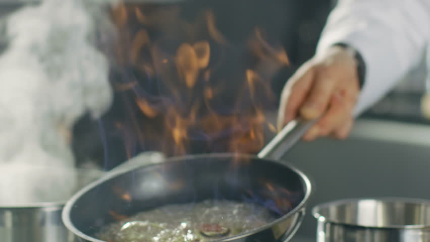 Close-up of a Chef Preparing Flambe Style Dish on a Pan. Oil and Alcohol Ignite with Open Flames.  Shot on RED EPIC-W 8K Helium Cinema Camera. Royalty-Free Stock Footage #28204231