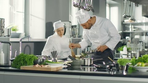 Famous Chef and His Female Apprentice Prepare Special Dish in a Modern Five Star Restaurant's Kitchen.   Shot on RED EPIC-W 8K Helium Cinema Camera.