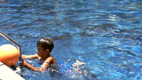 Young boy swiming with ball