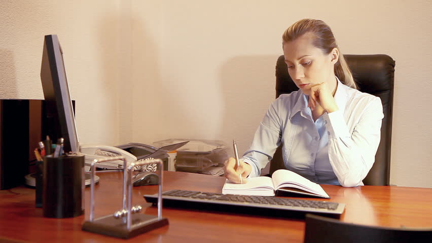Businesswoman sitting on the desk and working with notebook