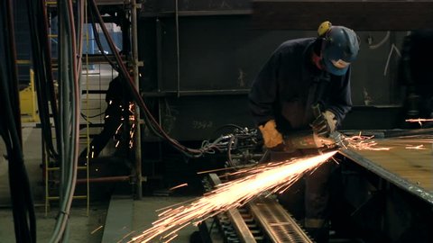 Man polishing in shipyard with protective equipment