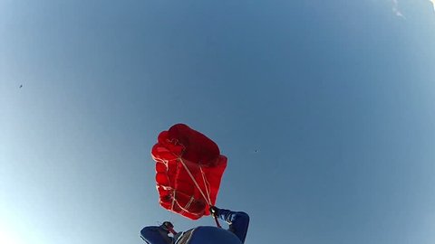 Skydiver pilots its parachute in the sky among the clouds.