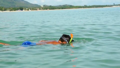 Young boy in the mask for diving swims in tropical sea