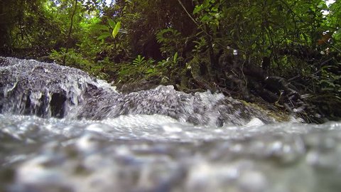 Water tumbles over an exotic. tropical waterfall. as the camera perspective slowly dives beneath the water's surface. with sound. FullHD video