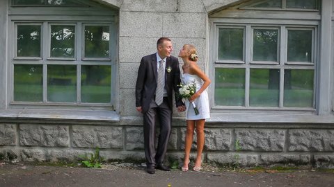 the bride and groom have fun and kiss in  front of a house 
