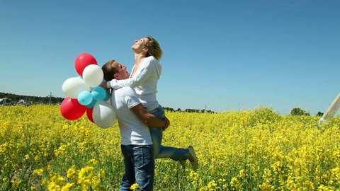 couple play with balloons in field
