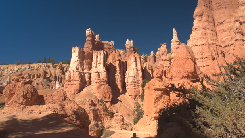 Unrecognizable woman hiker walking down the empty narrow path exploring majestic hoodoo formations in Bryce Canyon National Park in sunny Utah. Young woman tourist hiking dusty trail in Bryce Canyon