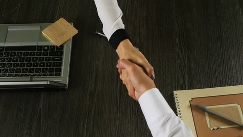 Female and man's hand against the background of a dark table. Top view of handshaking. 