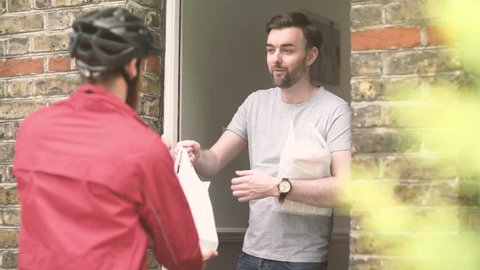 Food delivery at door. Takeaway food bags being delivered to door by delivery cyclist.