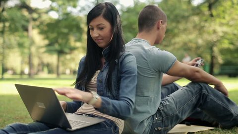 Happy female student with laptop in the park

