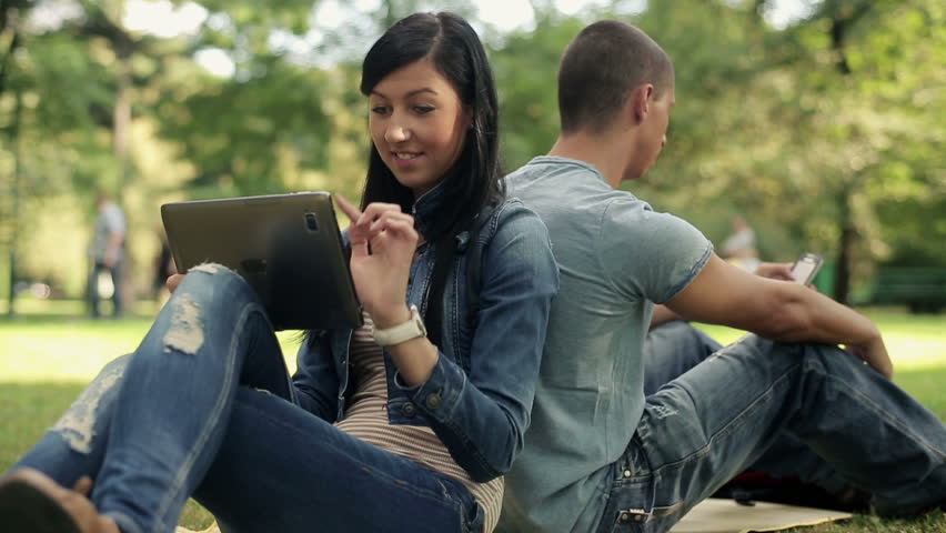 Young happy student with tablet computer in the park
