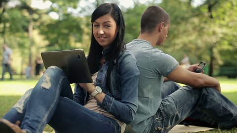 Young happy student with tablet computer in the park
