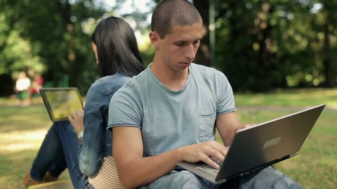 Young students with laptop and tablet in the park
