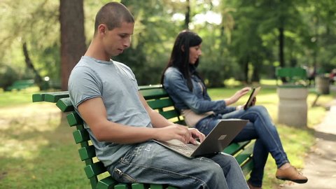 Young happy student with laptop in the park
