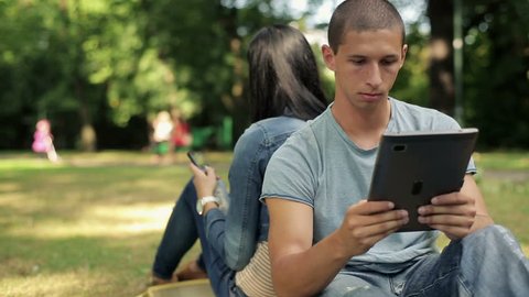 Young happy student with tablet computer in the park