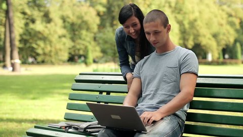 Young happy students with laptop in the park
