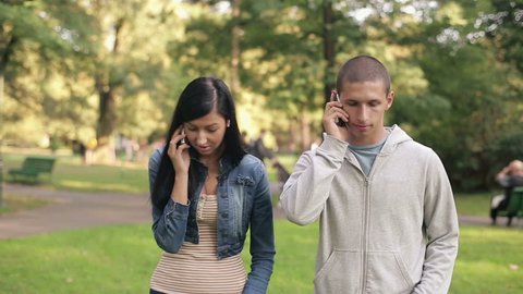Young couple talking on cellphone in the park
