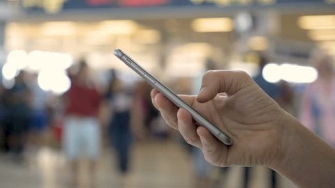 Airport traveler using cell phone in busy airport terminal