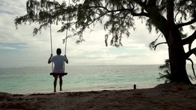 Man on a swing on tropical island beach enjoying his summer vacation in Punta Cana, Dominican Republic