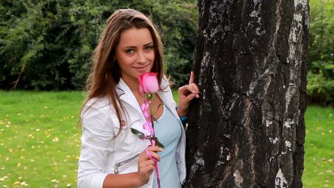 Beautiful girl posing with rose in the park.
