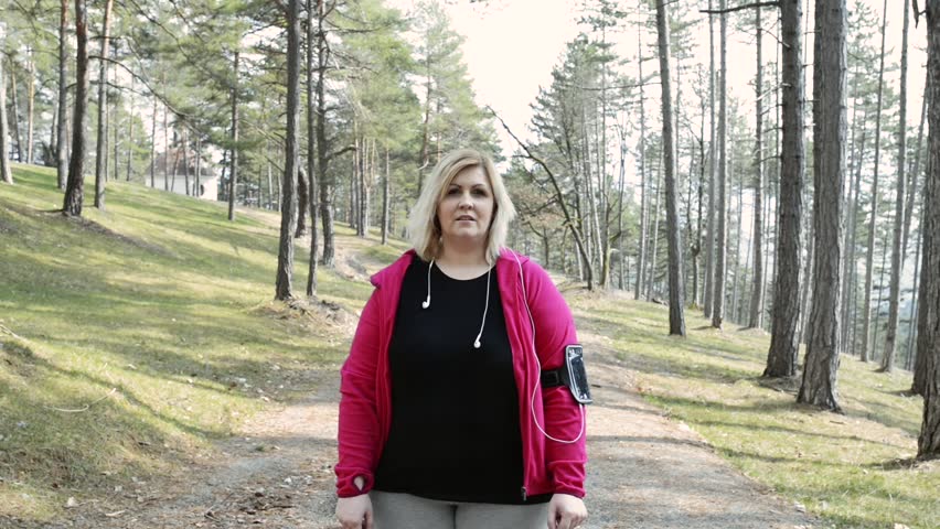 Attractive overweight woman in park doing stretching before running.