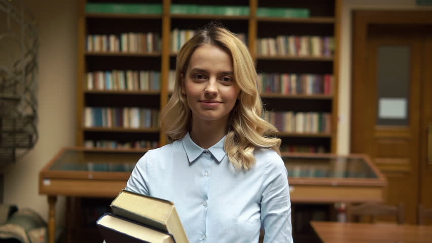 Student walks with large book in the library