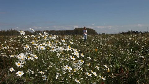Boy walks on the field with daisies