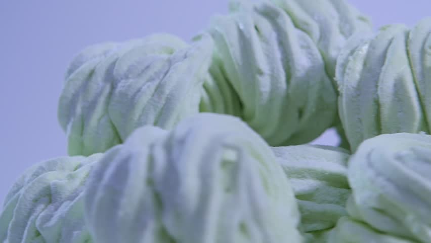 Fluffy white marshmallow in blue round bowl on old wooden table with copy space close up. Close up of many plump sweet round marshmallows on white plate. Polka dots background. Side view
