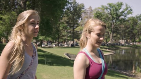 Steadicam Shot Of Fit Young Women Talking/Laughing And Walking Through Park On Their Way To Yoga Class