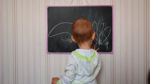 baby draws on chalkboard