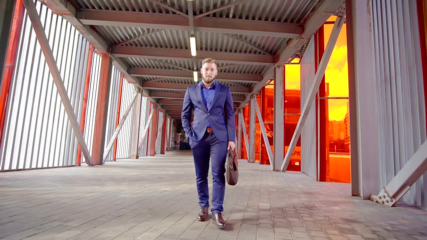 Businessman walking on the transition in the business district and using a mobile phone to talk and do business.
