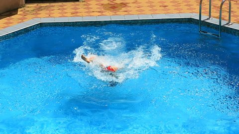 The child is swimming in the blue water of the pool. view from above. Girl dives under the water in the pool