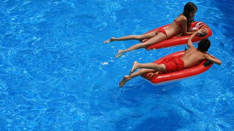 Children, a boy and a girl are floating on inflatable mattresses in the pool. view from above.