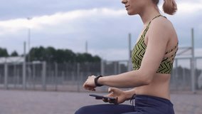 Woman in fitness suit checks her phone and fitness bracelet