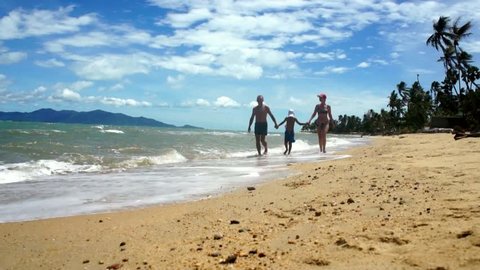 Family go for a walking along sand beach