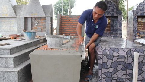 Worker installing Tile to a grave wall