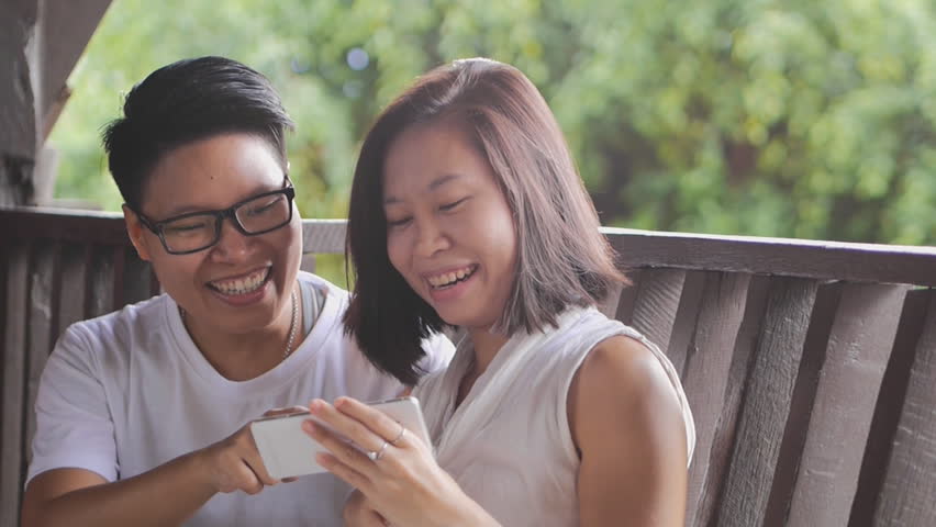 couple friend watching using mobile phone happy funny laughing together in natural nature garden background HD 1920 x 1080