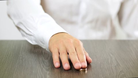 A man in a white shirt takes off an engagement ring from his finger. Decision on divorce.