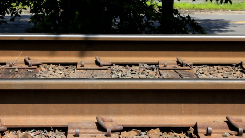Closeup of train wheels rolling on track, includes ringing bell