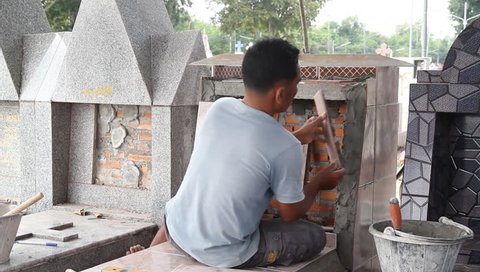 Worker installing Tiles to a grave