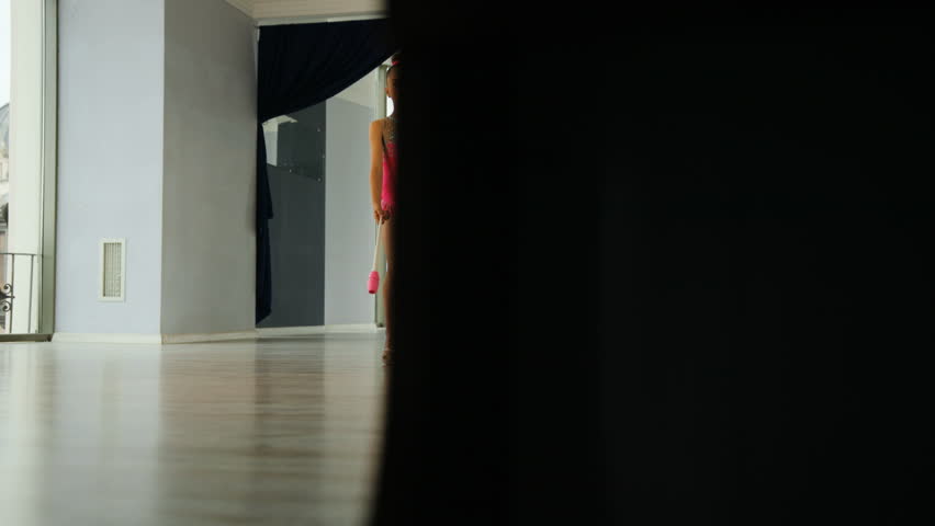 Young blonde hair girl doing exercive with mace in the hand in the studio on light window background. View from the bottom.