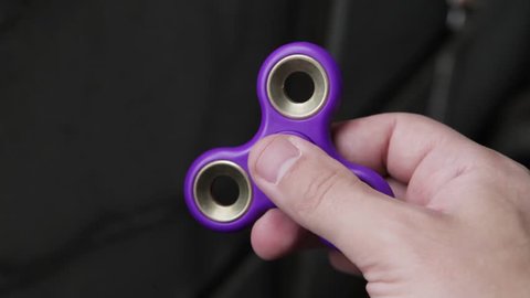 Playing with the purple Fidget Spinner. Toy spinner in hand.