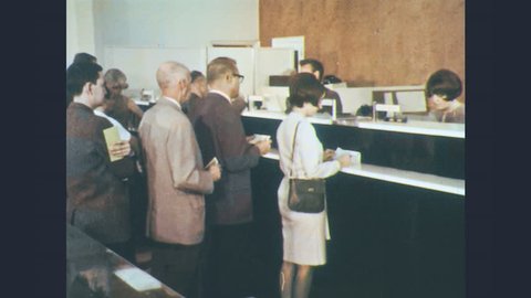 1960s: In bank, teller hands customer cash, customer counts. Man addresses viewer directly outside vault. Banker unlocks safe deposit box for customer. Customer banks with teller at drive-up window.