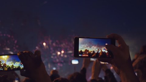 Hands of peoples taking photo to fireworks on smartphone. Close-up. Slow motion